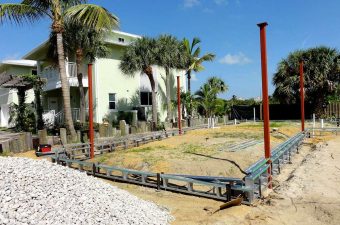 Construction site with metal frames and palm trees nearby.