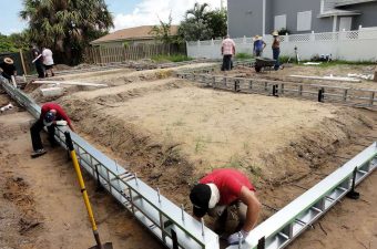 Workers prepare foundation forms for a construction project outdoors.
