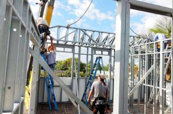 Team fitting steel roof trusses inside frame