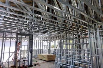 Interior view of a building under construction with metal framing and wooden beams.