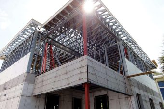 Modern building under construction with steel framework and concrete base.