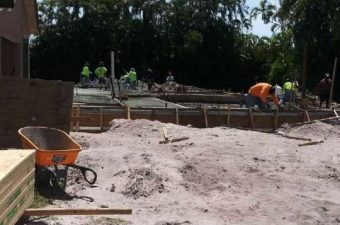 Construction site with workers preparing foundation and wheelbarrows.