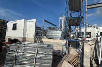 Construction site with scaffolding and building materials under a clear sky.