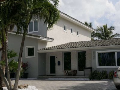 Modern two-story house with palm trees and a gray roof.