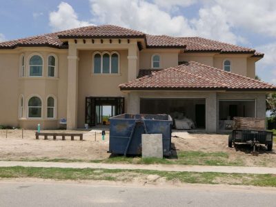 A large house under construction with dumpsters in front.