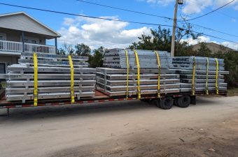Flatbed trailer loaded with stacked metal scaffolding on a rural road.