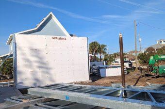 A large white tent structure with a peaked roof set up outdoors under a clear blue sky.