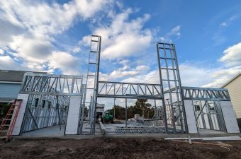 Metal framework of a building under construction against a blue sky.