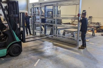 Forklift moving large glass panels inside a warehouse.