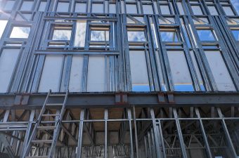 Construction site with metal framework and scaffolding under a cloudy sky.