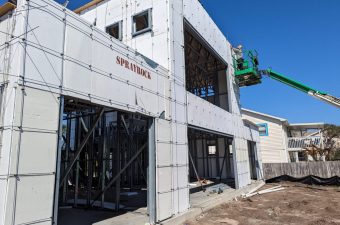 Construction site with workers installing exterior panels on a building.
