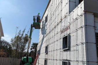 Construction workers installing insulation panels on a building exterior.