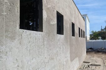 Building exterior wall with several windows under a clear sky.