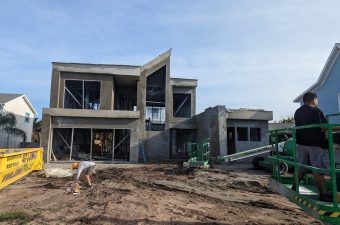 A two-story concrete house under construction with a clear sky.