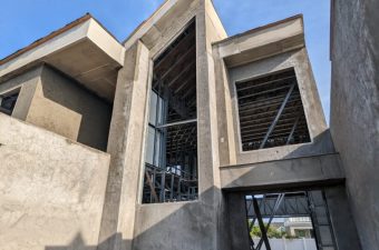 Modern concrete building under construction with sharp angles and open windows.