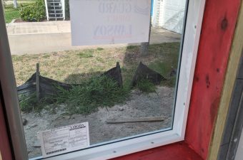 Window with a handwritten sign taped on it.