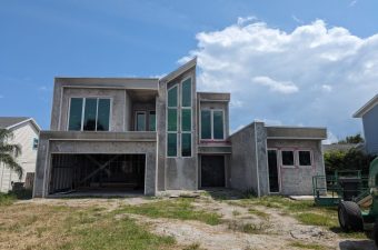 Unfinished modern house under a blue sky with some clouds.