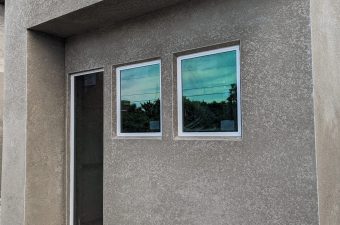 Newly constructed small concrete building with two windows and a door.