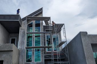 Construction workers building a modern concrete house with scaffolding.