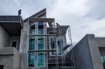 Construction workers building a modern concrete house with scaffolding.