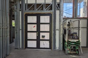 Interior view of a building under construction with framed walls and a large window.