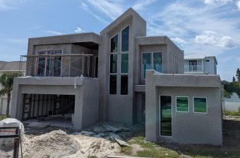 Modern house under construction with large windows and concrete structure.