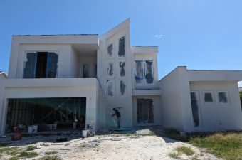 Modern white house under construction with artistic wall designs.