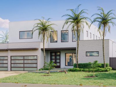 Modern white two-story house with palm trees and a large garage.
