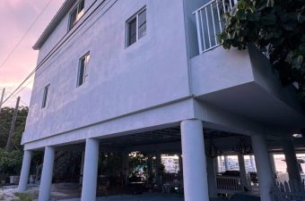 A raised house supported by multiple large white pillars in the evening light.