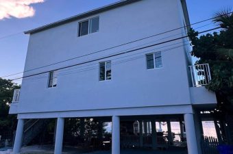 Elevated house with multiple windows and stilts for support.