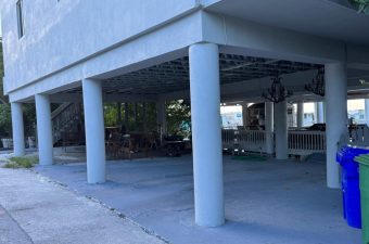 Empty concrete area under a building with supporting columns.