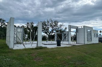 Open-air concrete structure under a cloudy sky with trees in the background.