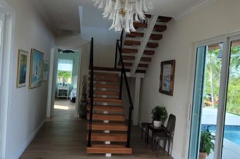 Modern hallway with wooden stairs and glass doors leading to a pool.
