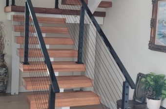 Modern indoor staircase with wooden steps and black metal railings.