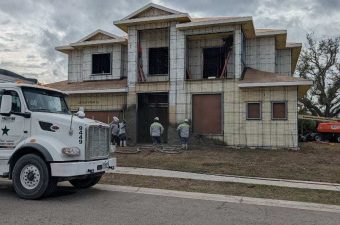 A house under construction with a truck parked on the street.