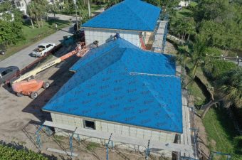 Aerial view of a house roof under construction with blue waterproofing.