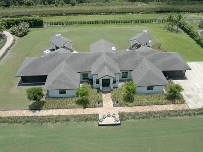Large luxury lakeside house with green surroundings and a boat dock.