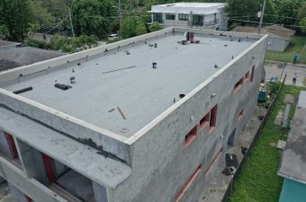 A flat rooftop of an unfinished concrete building with scattered materials.