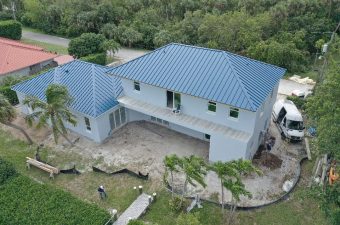 Large house with a blue metal roof under construction.