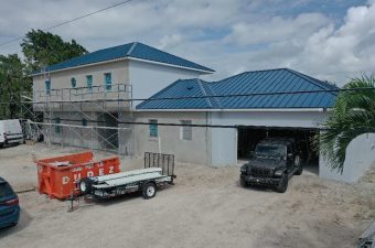 A building with a blue roof and vehicles parked outside under a cloudy sky.