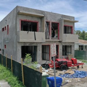 Two-story house under construction with scaffolding and building materials around.