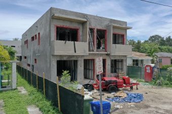 Two-story house under construction with scaffolding and building materials around.