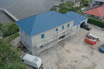 New two-story house under construction with blue roof and scaffolding.