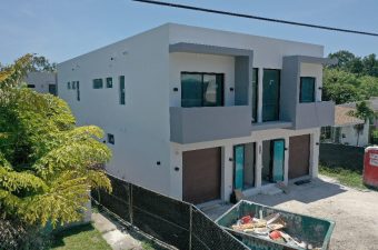 Modern white house with balcony and garden under construction.