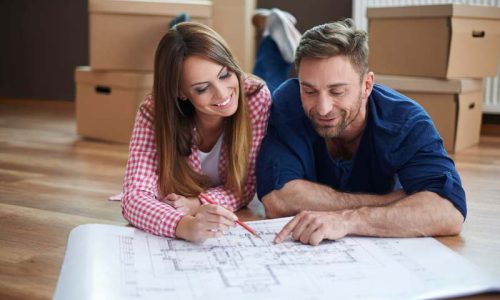Couple reviewing house blueprint on floor